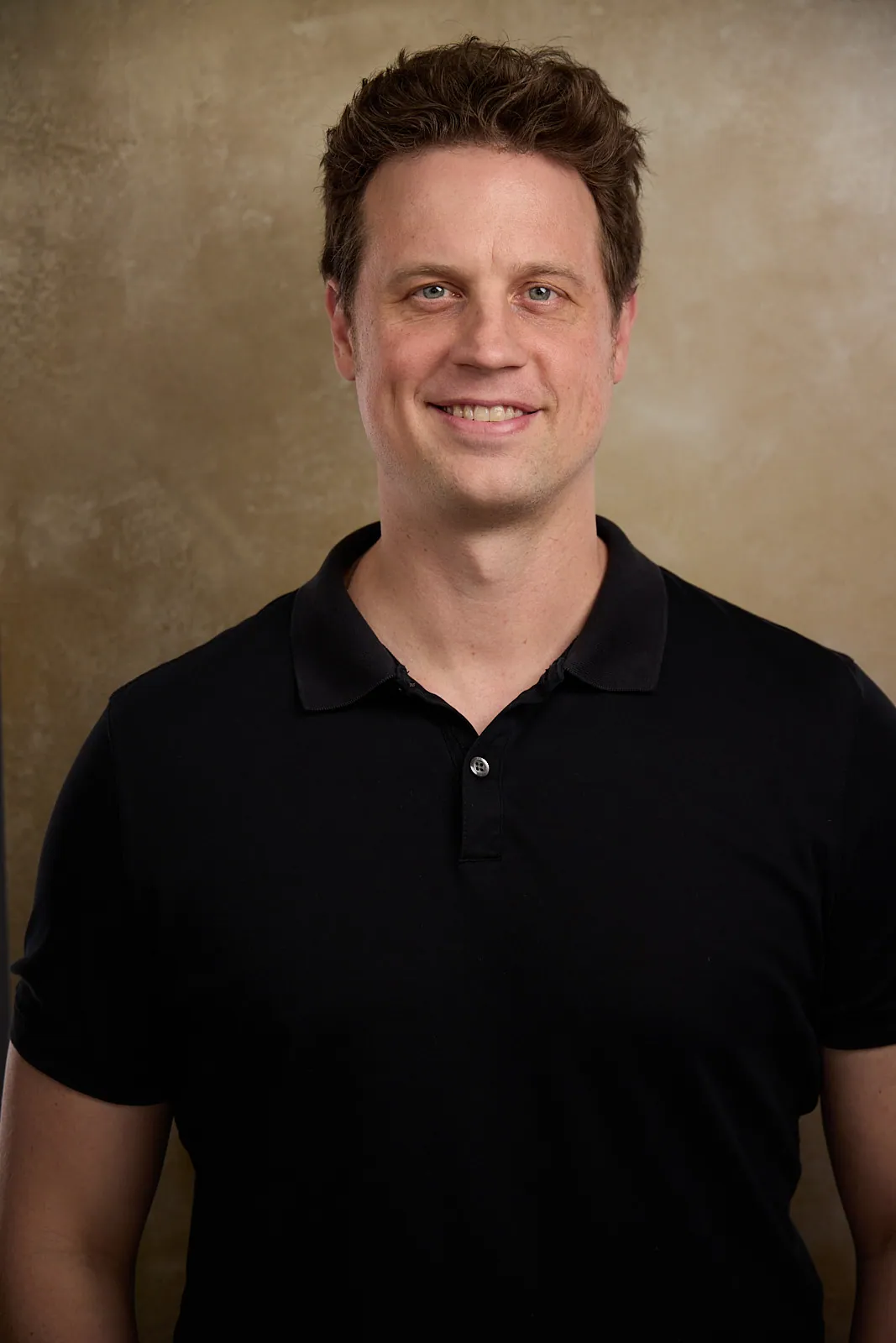 portrait of a man in a black shirt smiling