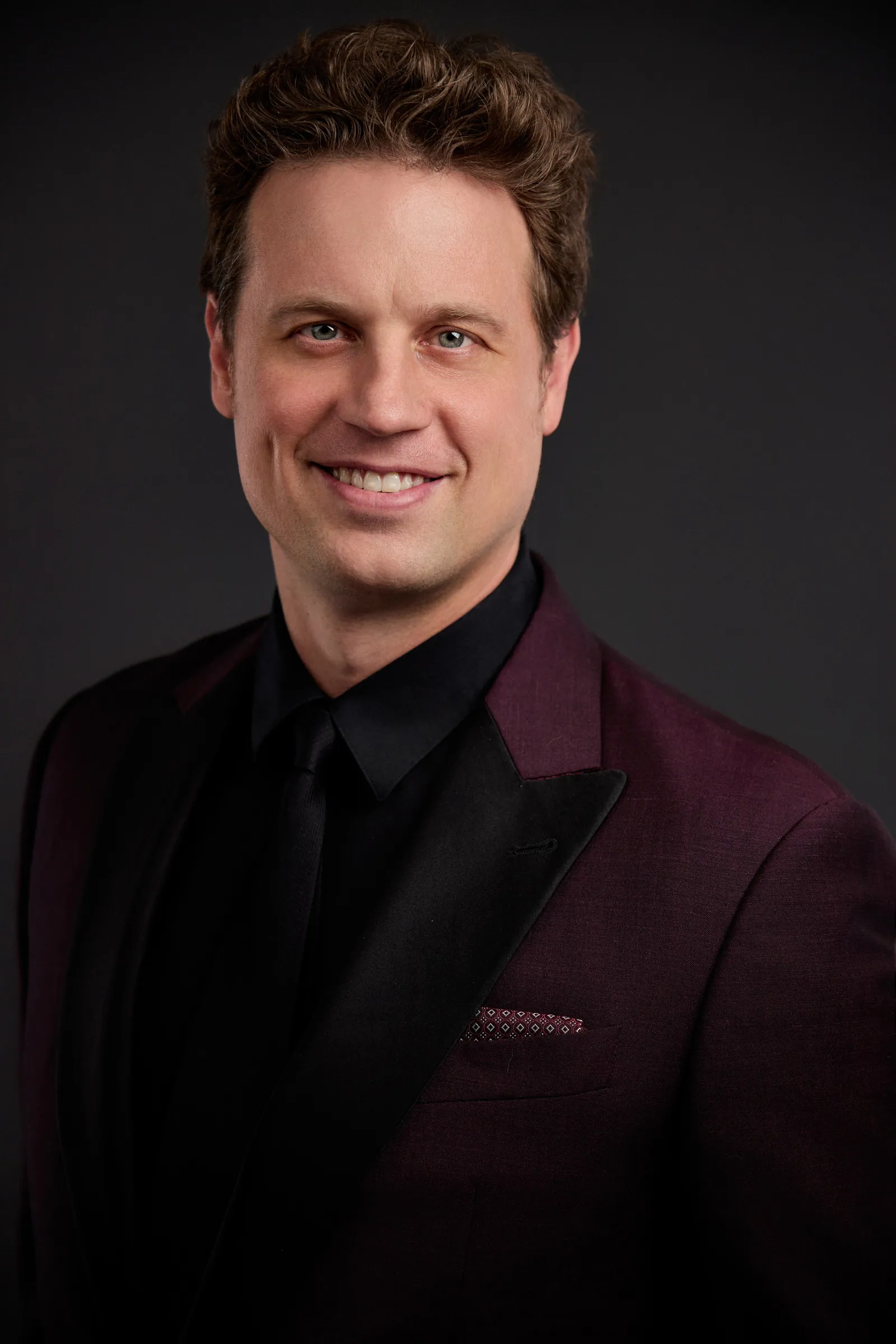 man in Burgundy business suit smiling